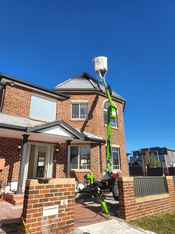 Roof painting of a two-storey brick home using a cherry picker